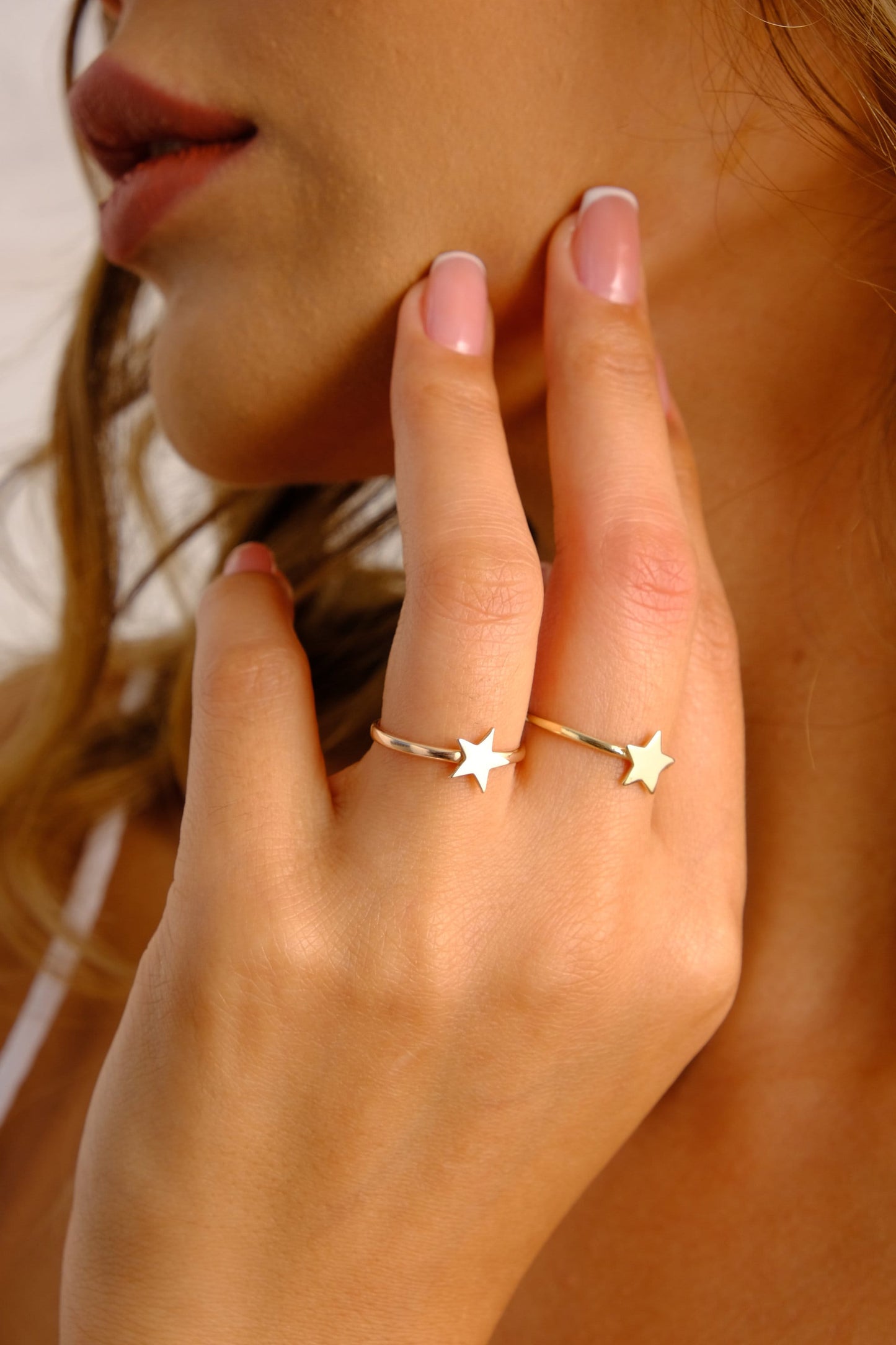 May include: Two gold rings with star-shaped designs. The ring on the left has a white star, and the ring on the right has a gold star.