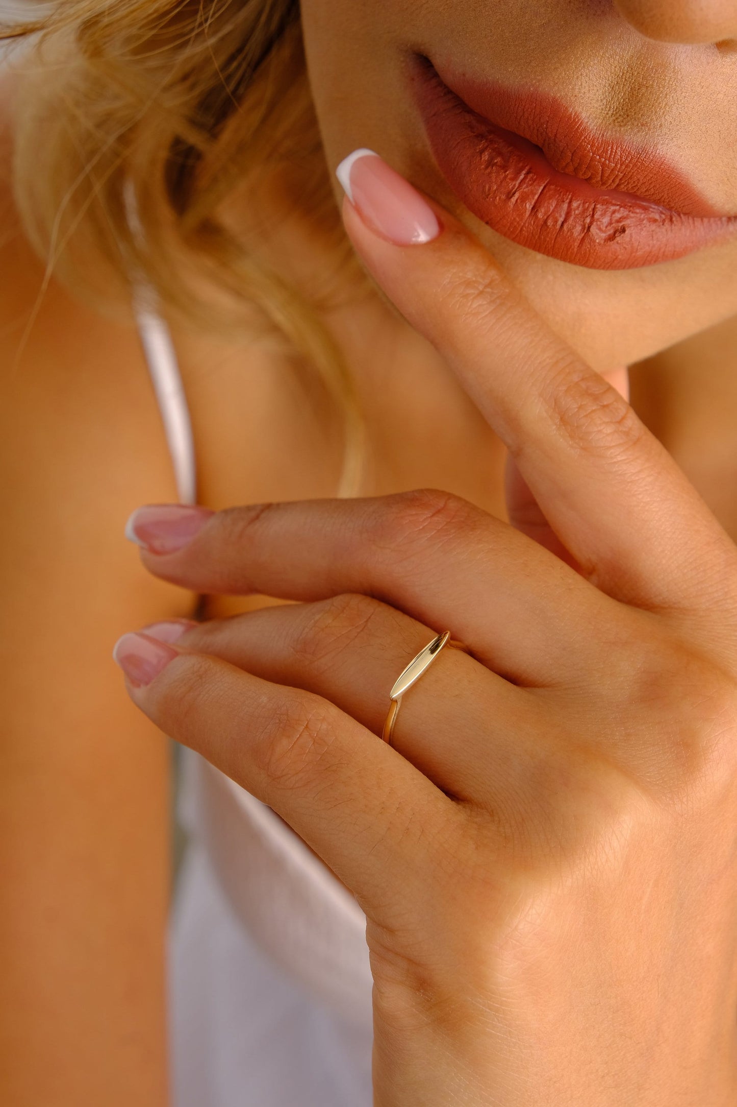 May include: A gold ring with a thin, flat, rectangular band and a slightly curved, elongated, rectangular top.