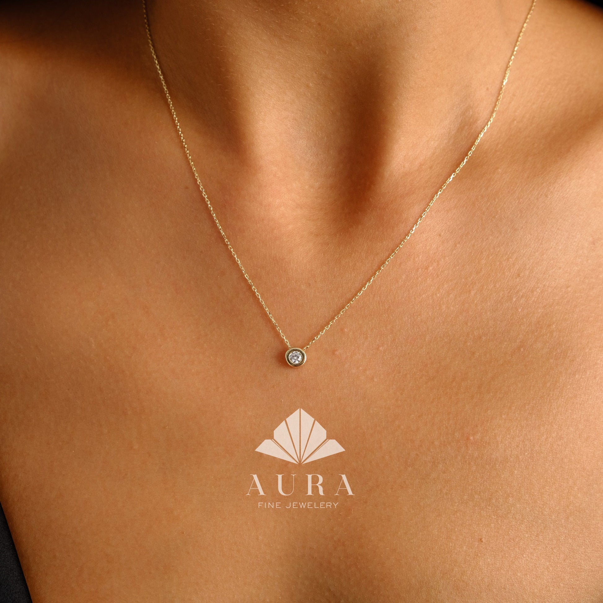 May include: A delicate gold chain necklace with a small, round, bezel-set diamond pendant.