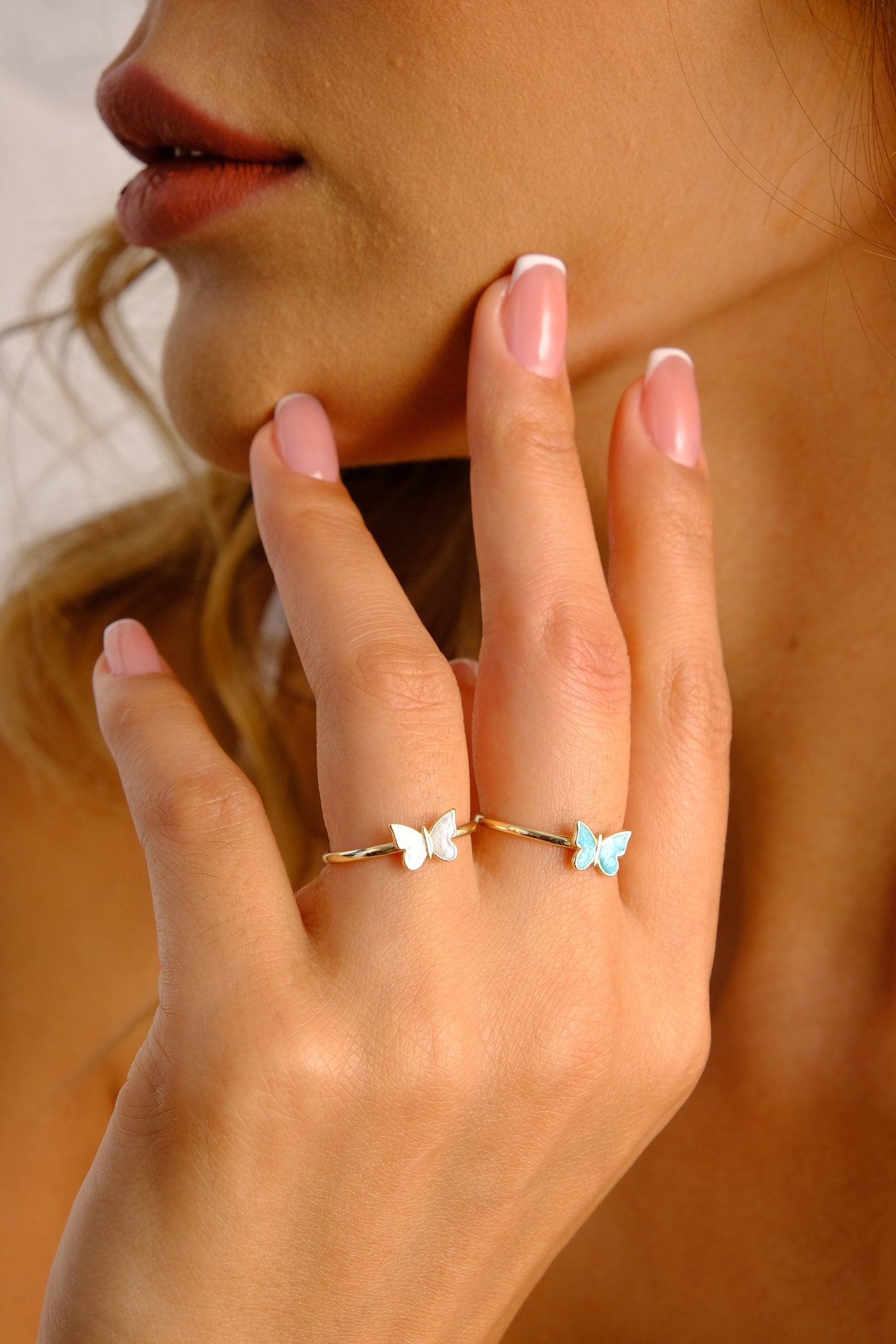 May include: Two gold butterfly rings. One ring features a white butterfly, and the other ring features a light blue butterfly.